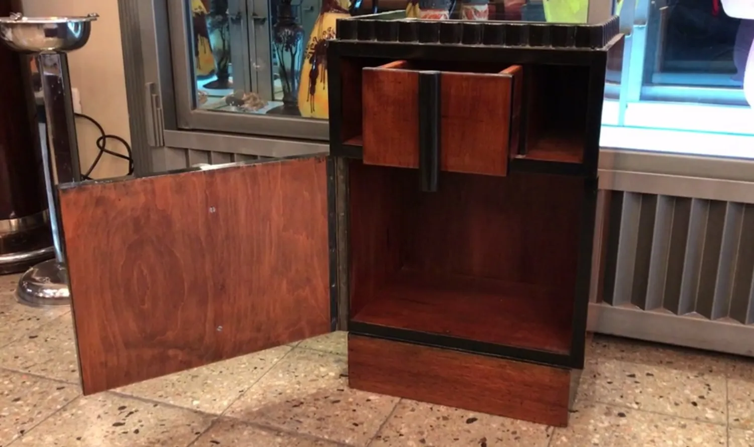 antique bedside table with drawers and decorative door.