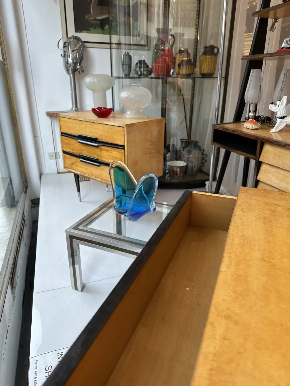 Antique bedside table with drawers and colorful tableware.