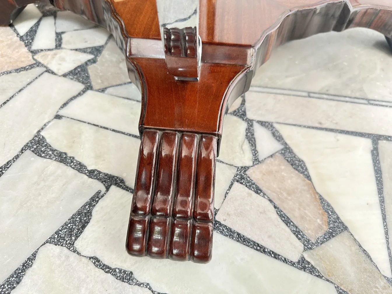 detail of an antique small table leg on a stone floor.