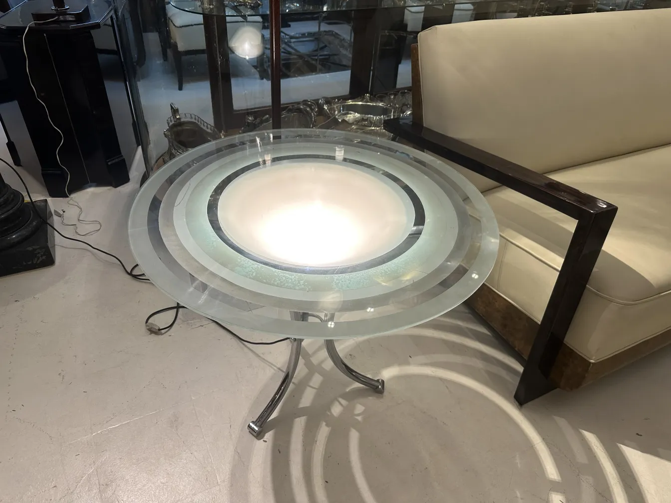 Round antique small table with center light, next to a light sofa