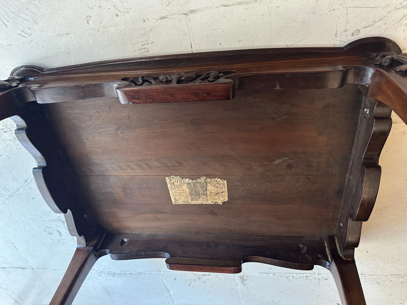 Antique small table with decorative features and a label.