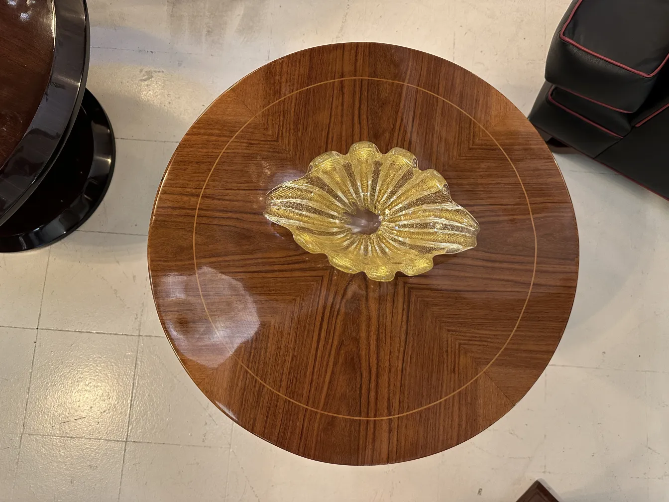 Antique small table with a decorative yellow item in the center, featuring intricate design.