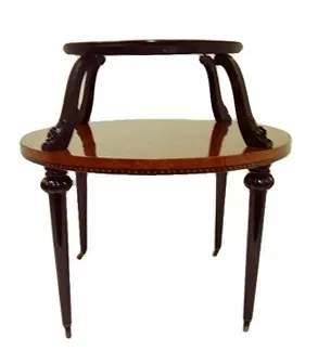 Antique small table with an upper tray and elegant legs, in an antique setting.