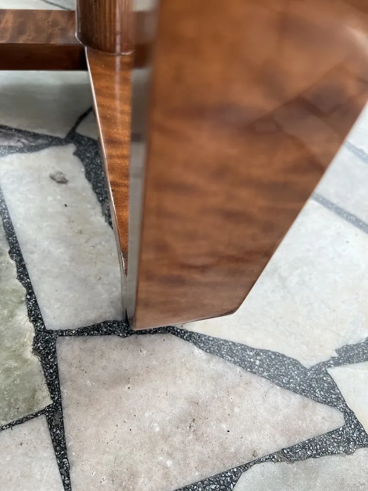 Detail of a small antique table with decoration rising from the ground.