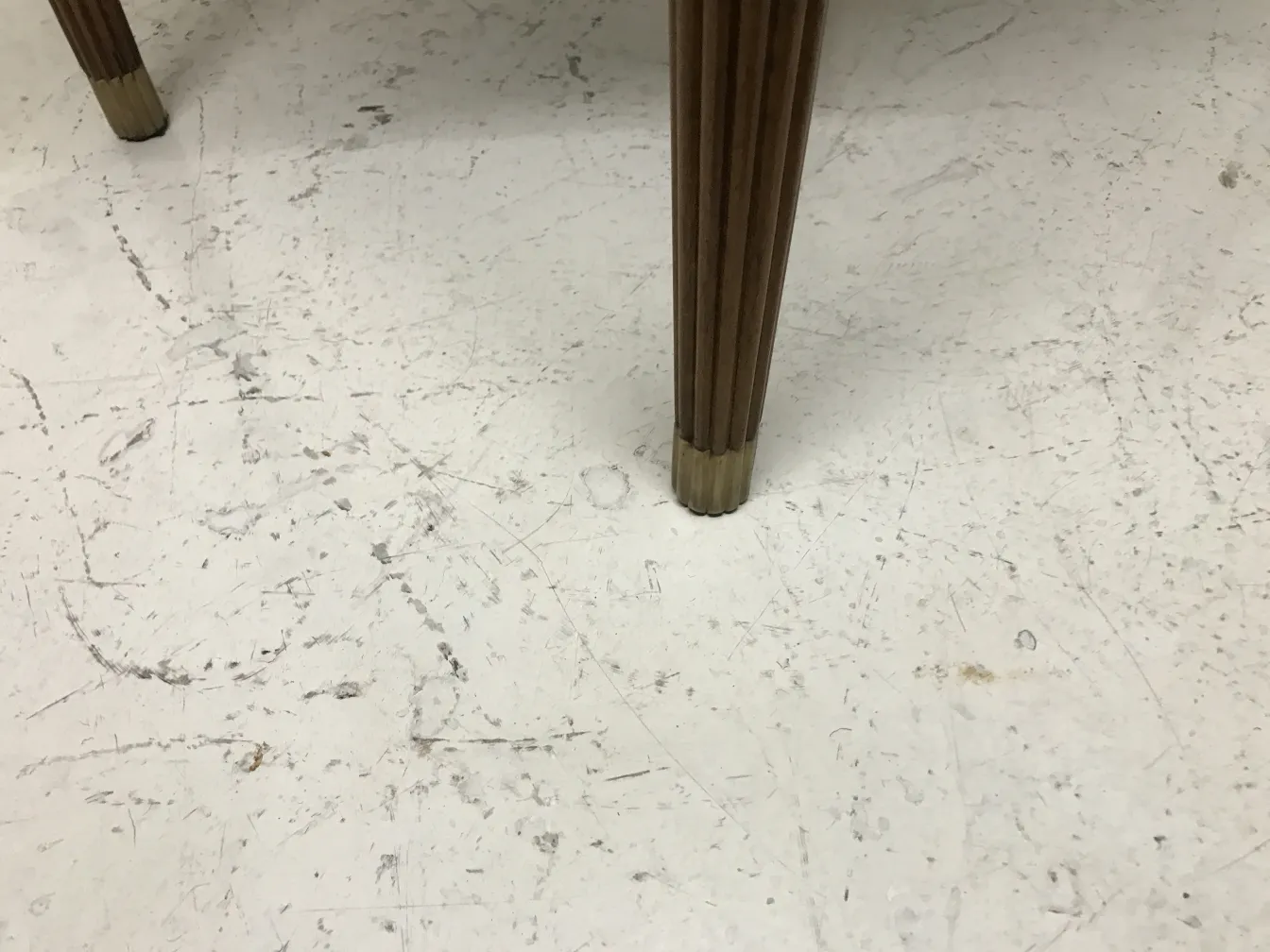 View of an antique small table with slim legs in a neutral setting.