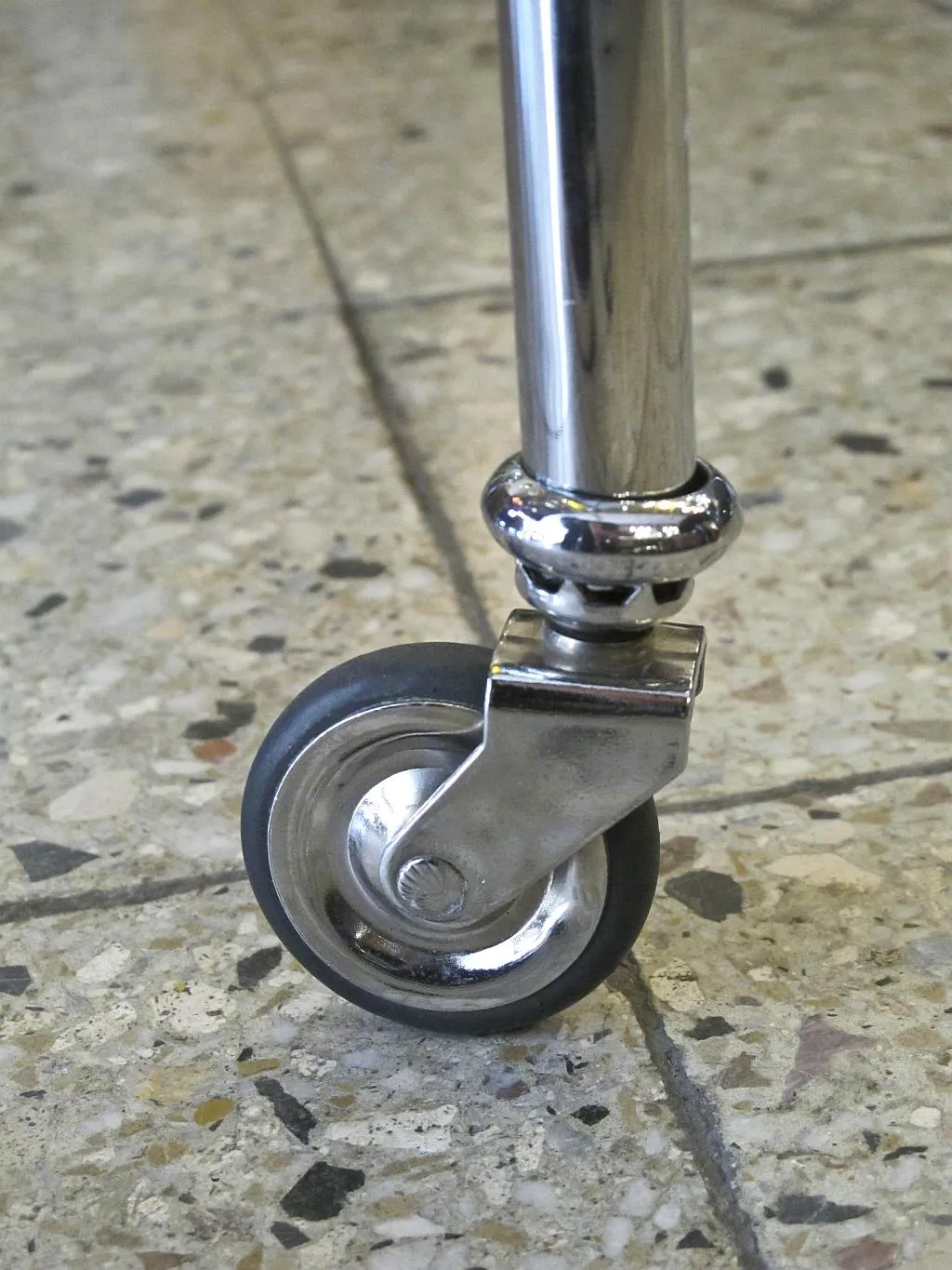 Close-up view of an antique small table with wheels on the floor