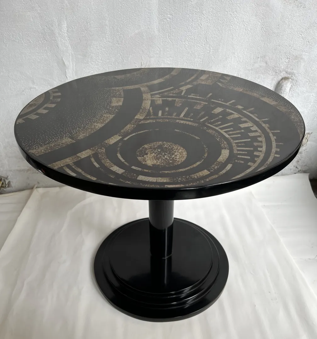 Antique small table featuring a circular top with decorative patterns and a black base.