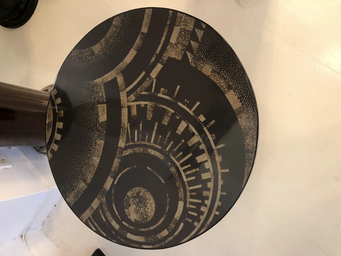 Antique small table with a round top and geometric patterns in dark tones