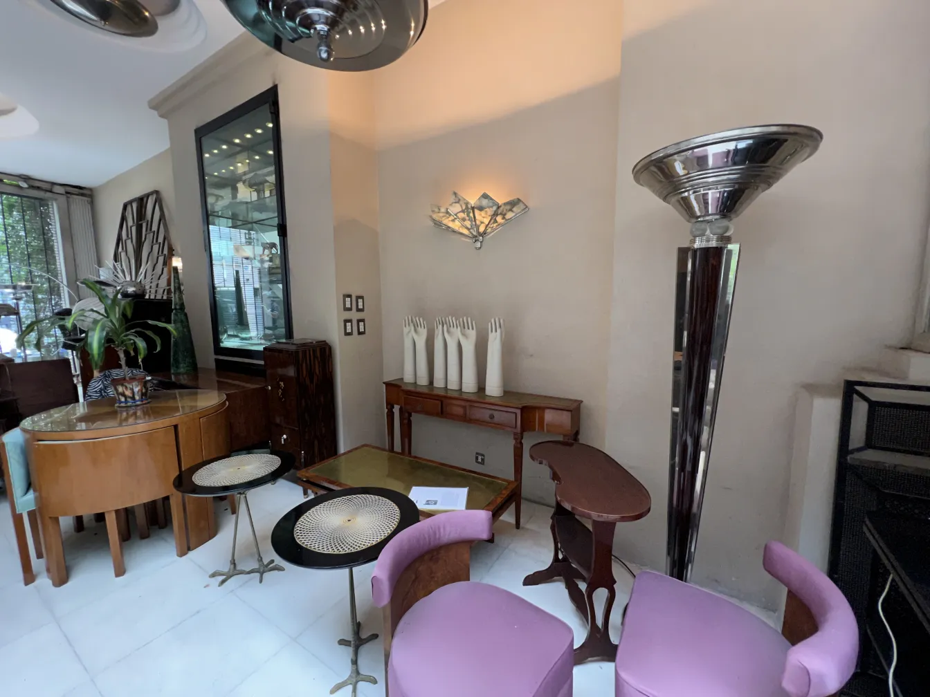 An antique small table in an elegant living room with chairs and plants