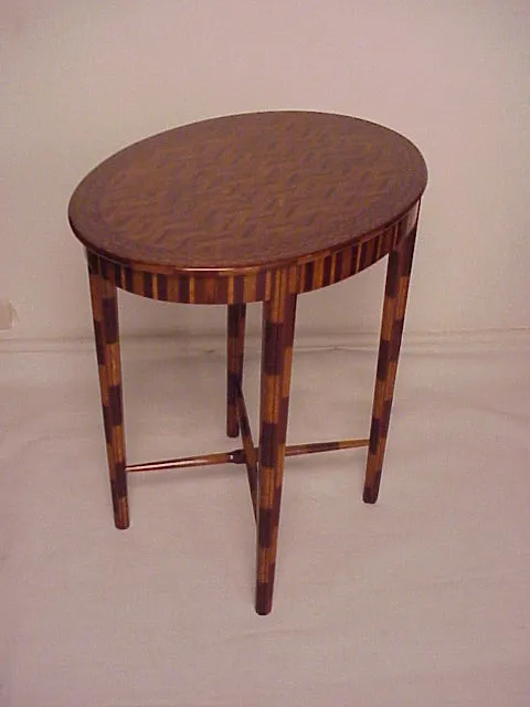 Antique small table with an oval shape and slender legs, elegant design.