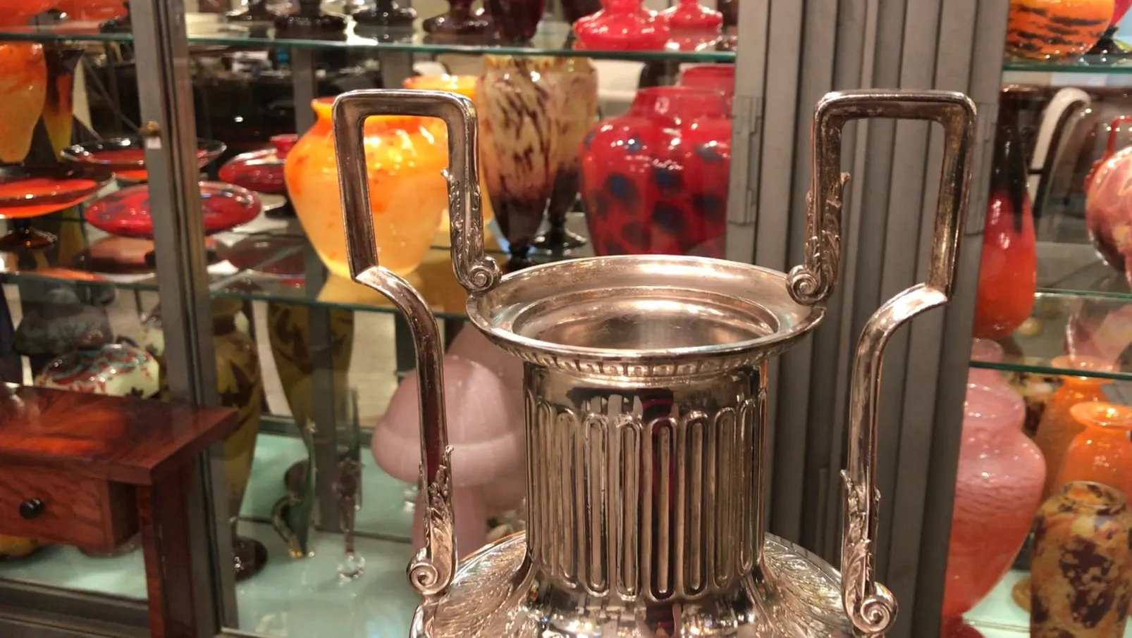 Antique decorative vases with engraved details and handles, surrounded by colorful ceramic pieces.