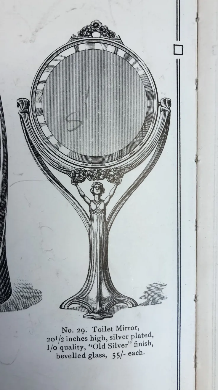 antique mirror featuring an artistic design on the frame and an elegant stand.