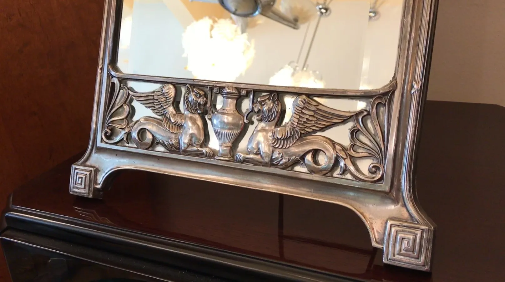 Antique mirror with double winged figure detail on the frame.