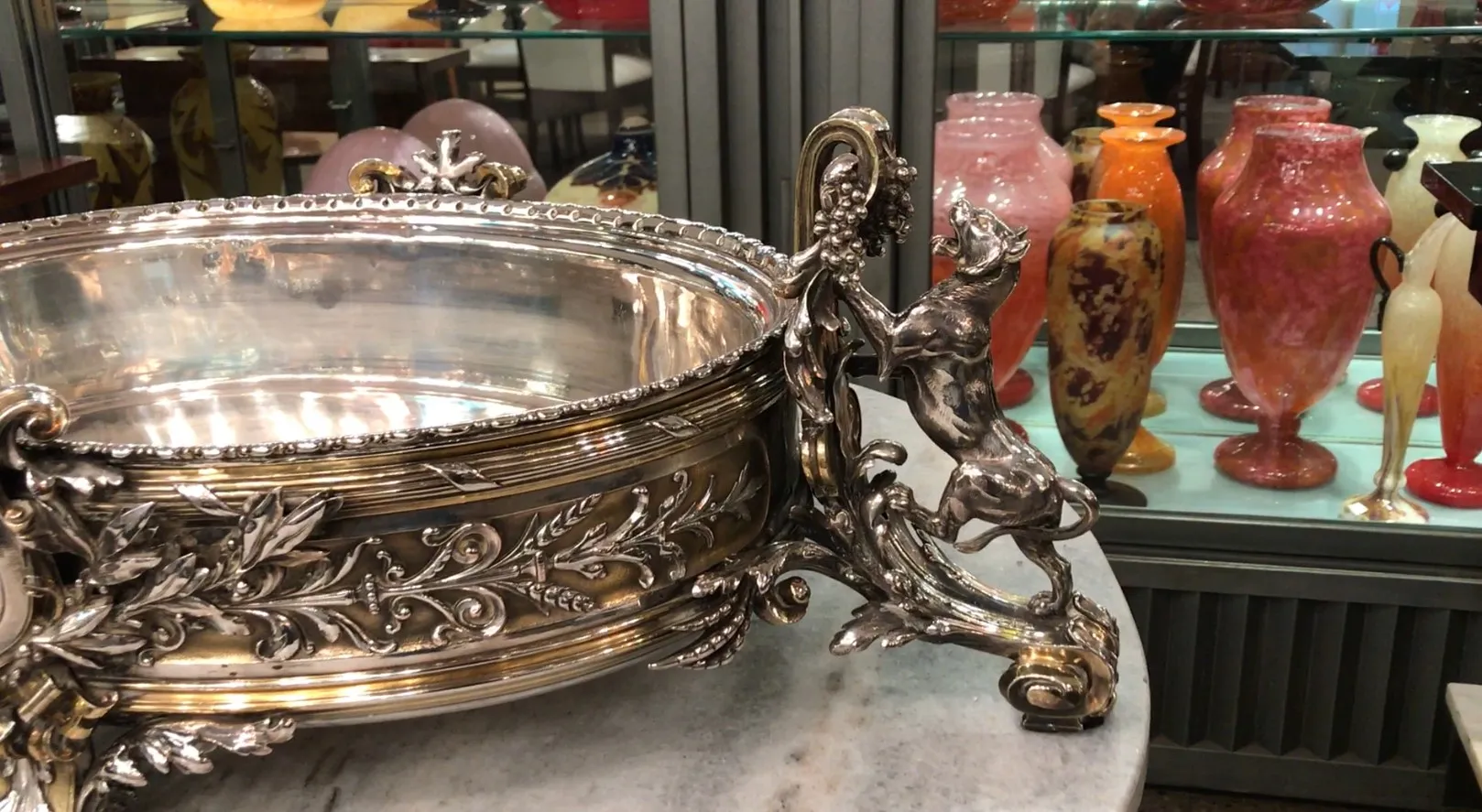 antique centerpiece Christofle with decorative design and intricate details, background with colorful vases.