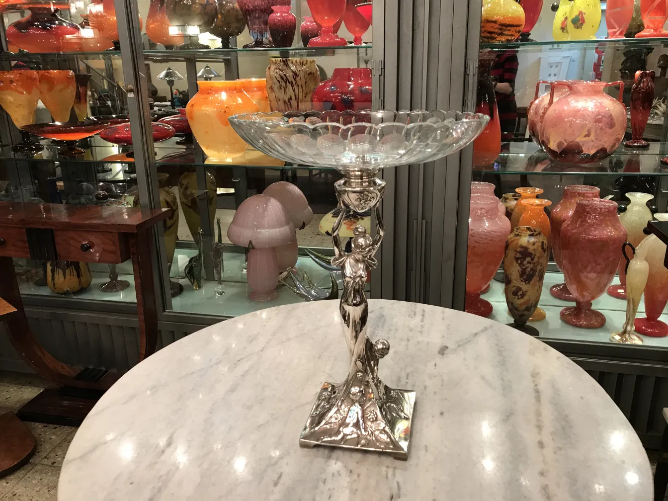 Antique WMF centerpiece displayed elegantly with colorful vases in the background.