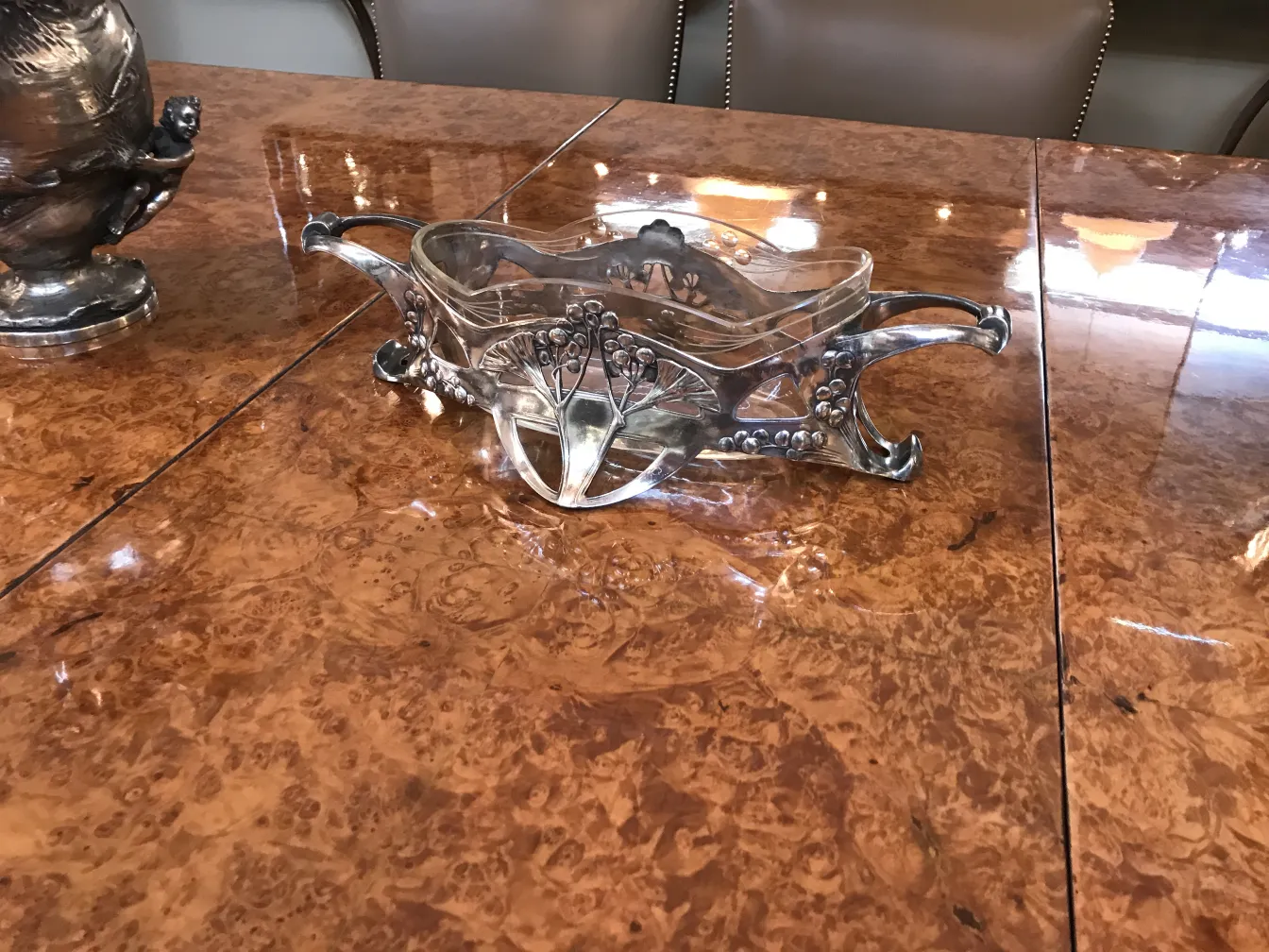 Antique WMF centerpiece on a polished table, featuring floral details.