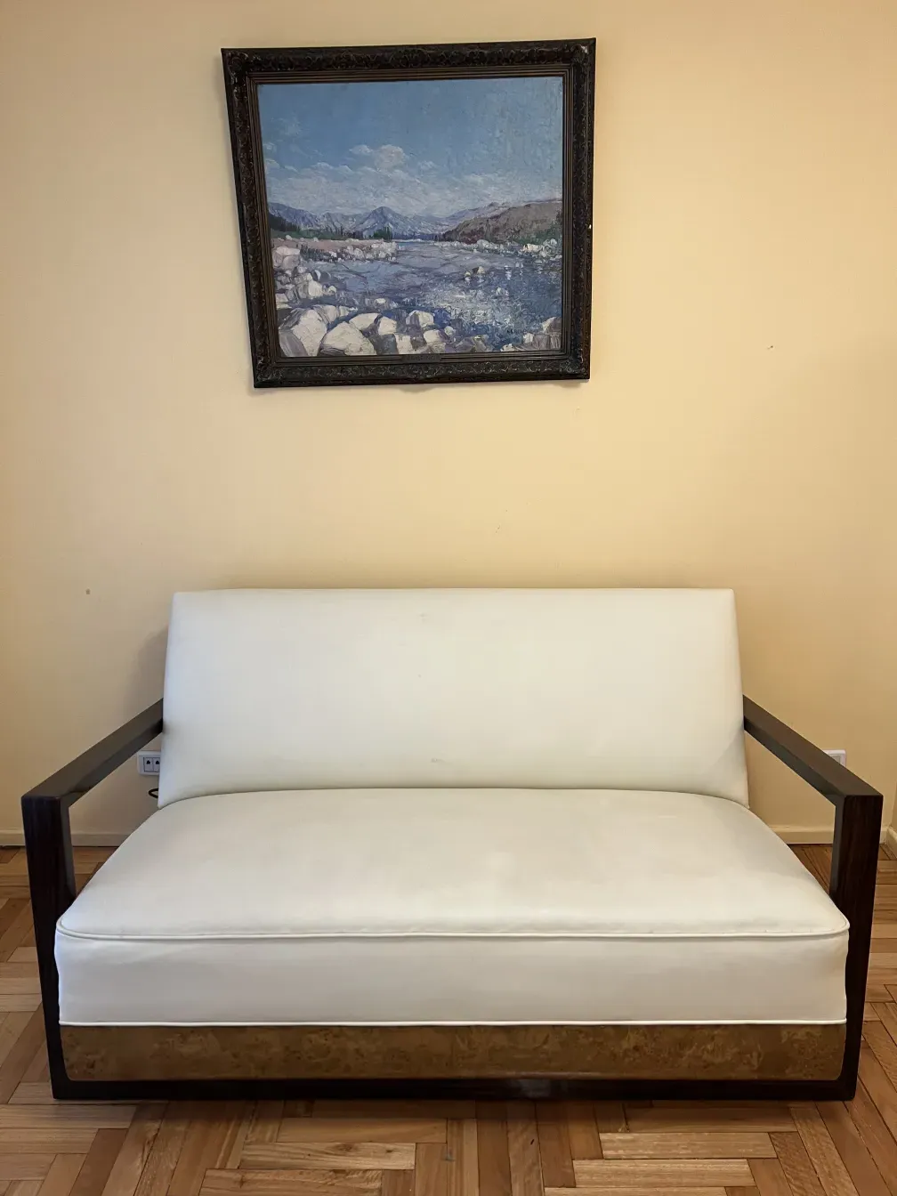 Antique light-colored armchair with distinctive arms in a cozy setting.