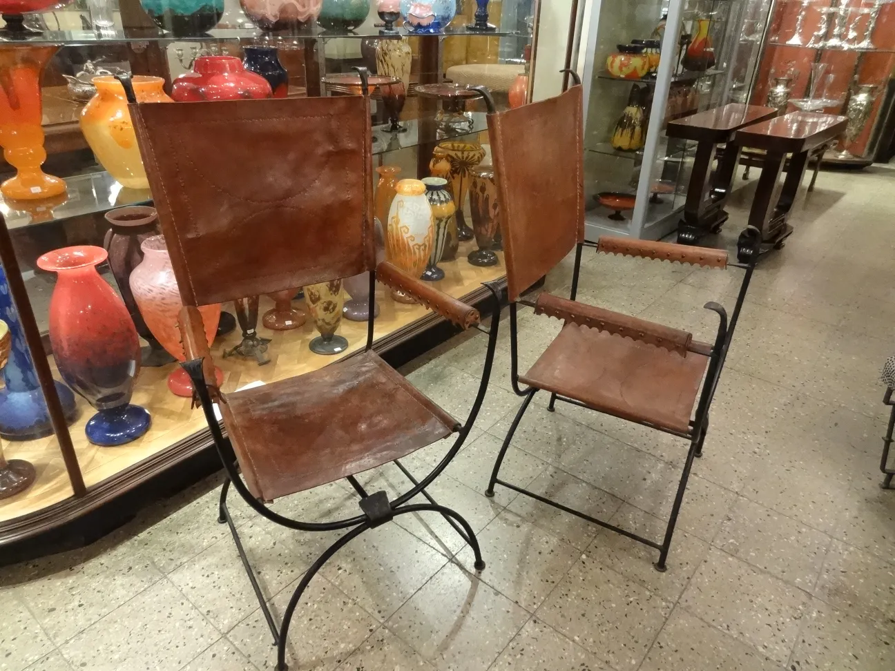 2 antique armchairs with arms, displayed in a decorative showcase