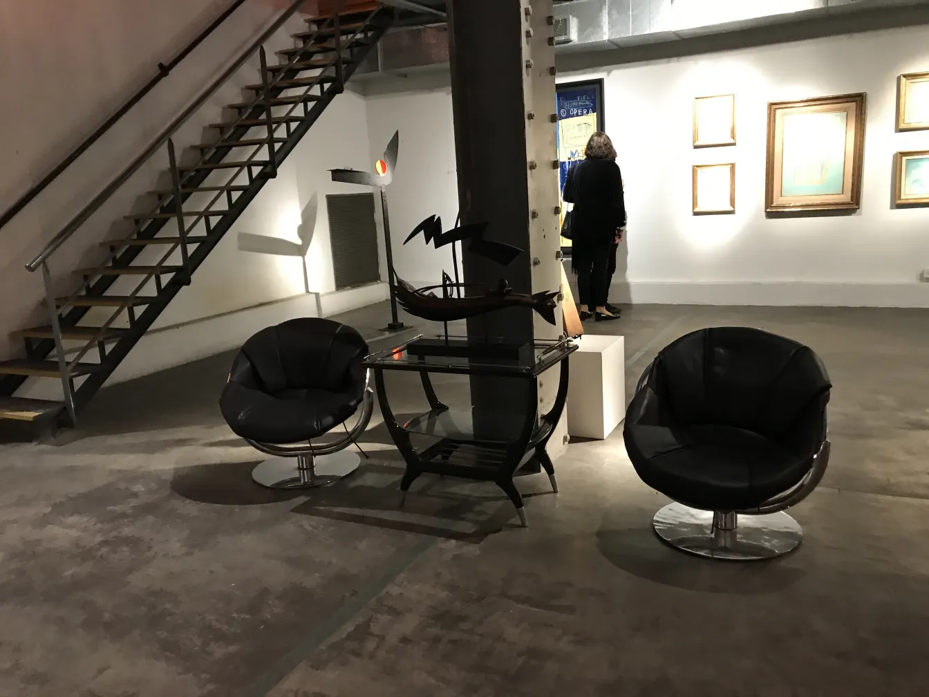 two antique armchairs in a modern setting with stairs and art