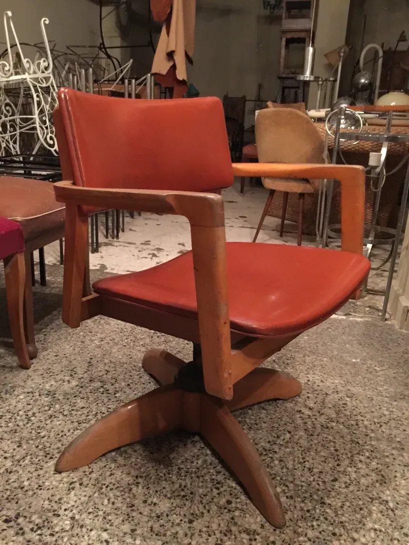 Poltrona da ufficio antica con seduta arancione in un ambiente d'antiquariato