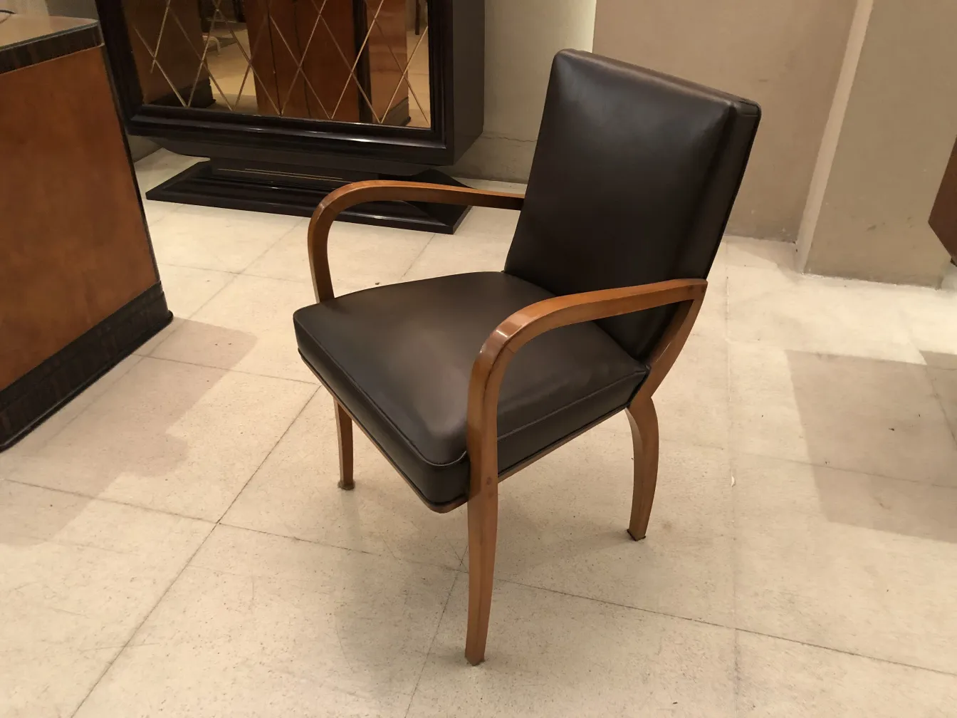 Poltrona da ufficio antica in marrone, con braccioli in legno in un ambiente elegante.