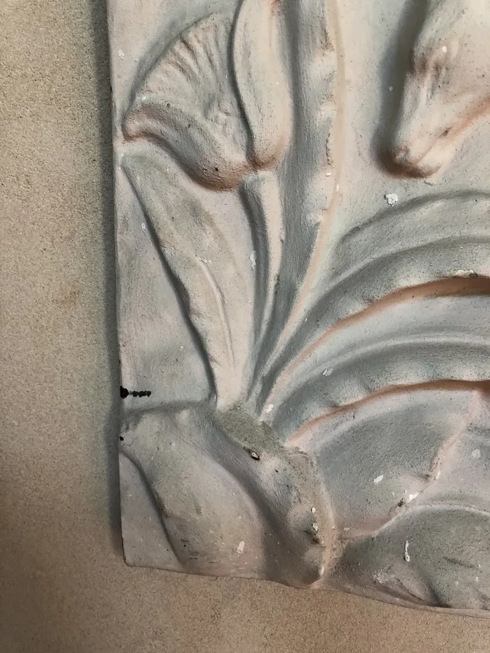 Placa de parede antiga com detalhes em relevo, apresentando decorações suaves e padrões elegantes.