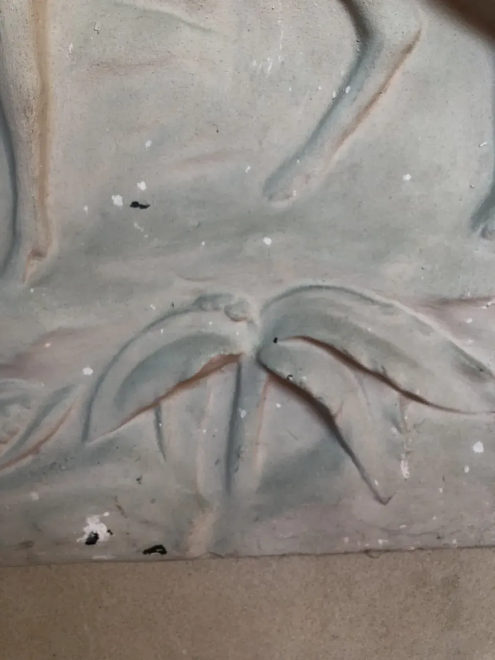 Placa de parede antiga com relevos de folhas e padrões florais