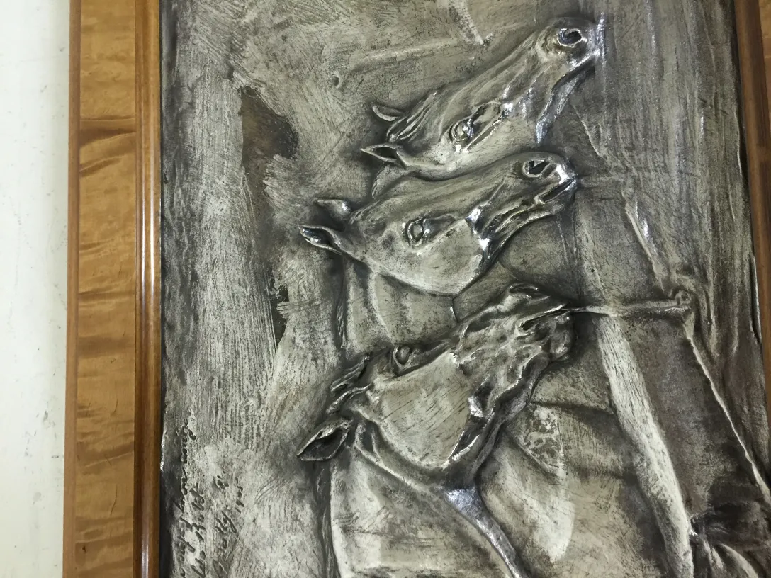 Placa de parede antiga com design de cavalos em relevo.