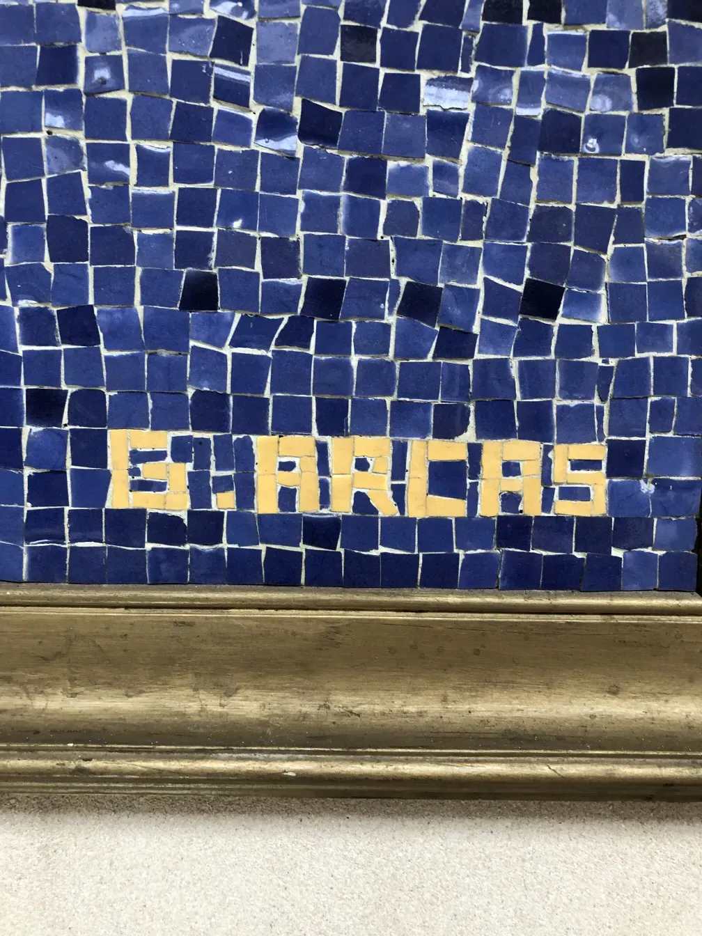 Quadro de mosaico antigo com azulejos azuis e amarelos, ambiente clássico.