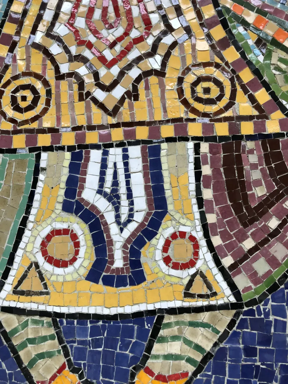 Detalhe de um quadro de mosaico antigo colorido com padrões variados.