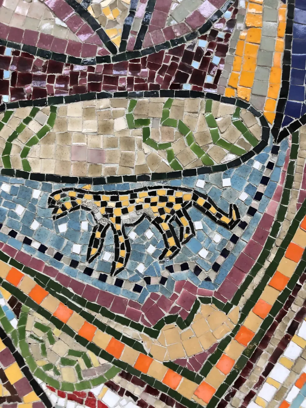 Quadro de mosaico antigo com cores brilhantes e formas variadas.