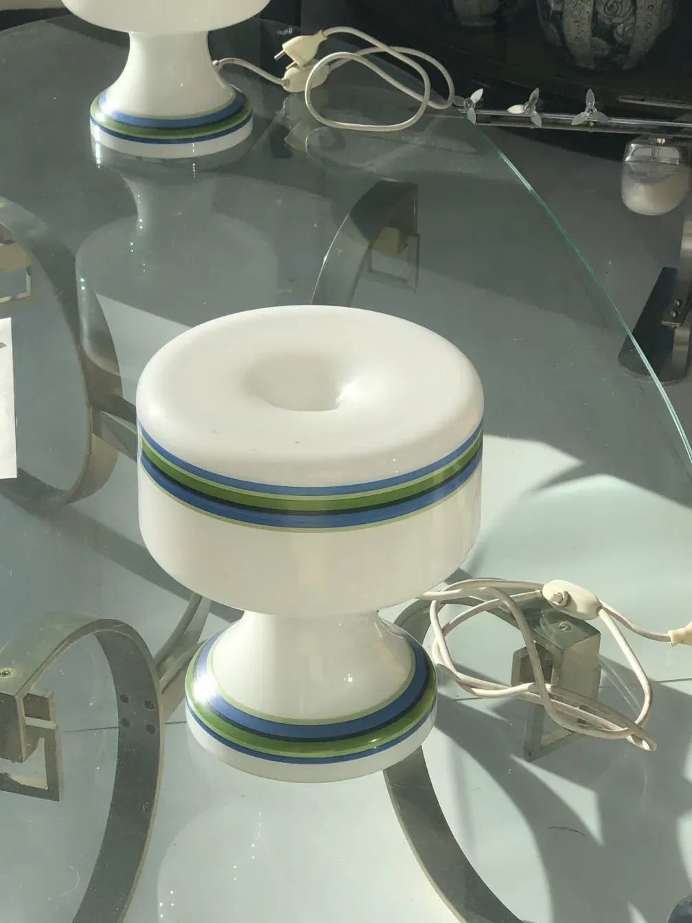 Vista de 2 lâmpadas de mesa antigas com detalhes coloridos. Ambiente aconchegante.