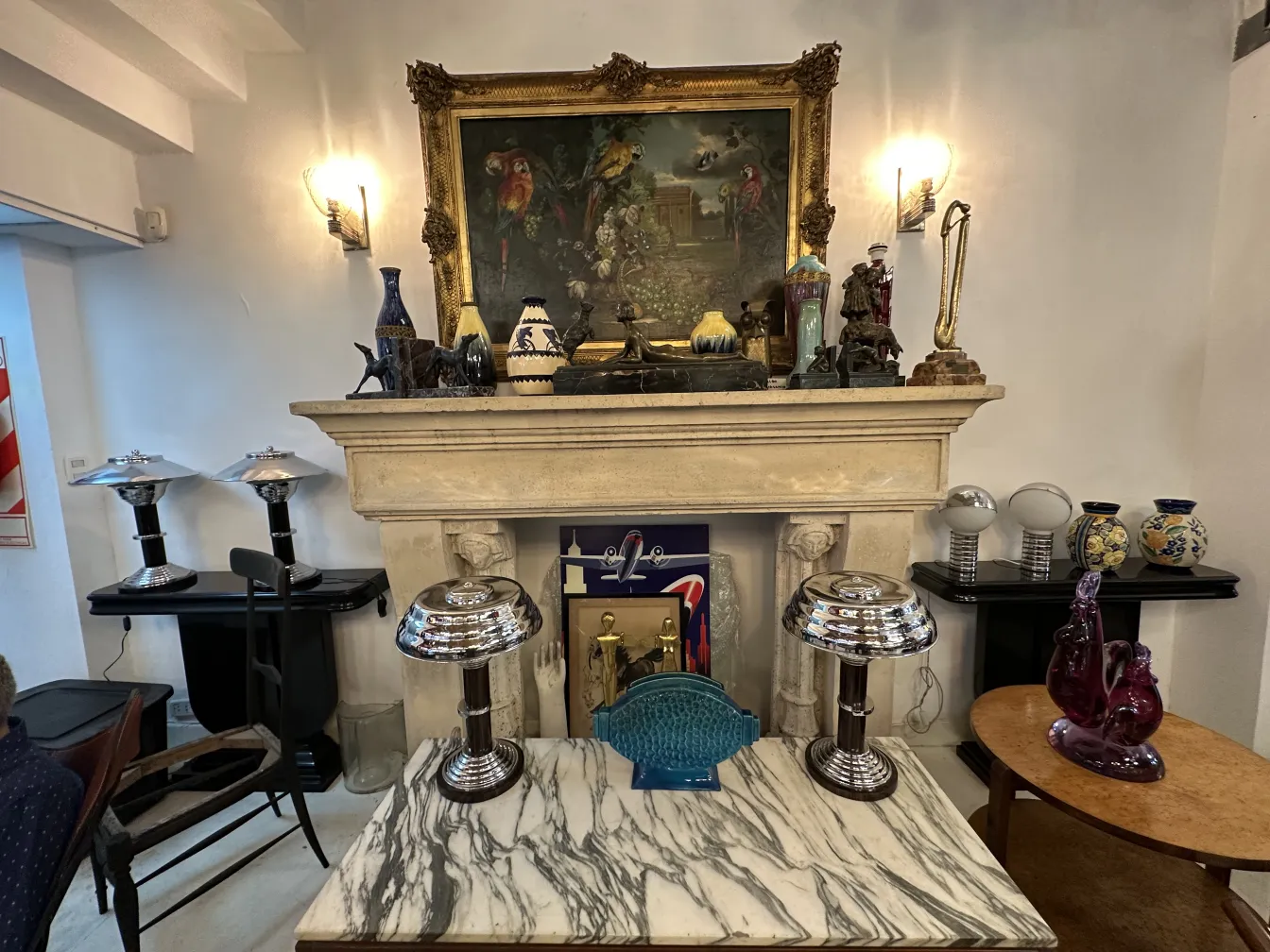 2 lâmpadas de mesa antigas sobre uma mesa de mármore, com bases brilhantes e um ambiente decorativo variado.