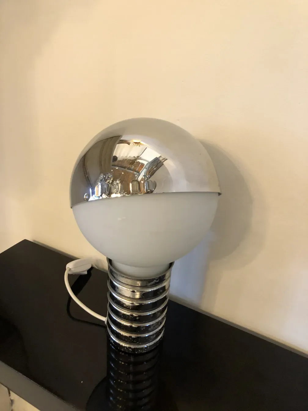 2 antigas lampadas de mesa com esfera brilhante e base preta, em um ambiente minimalista.