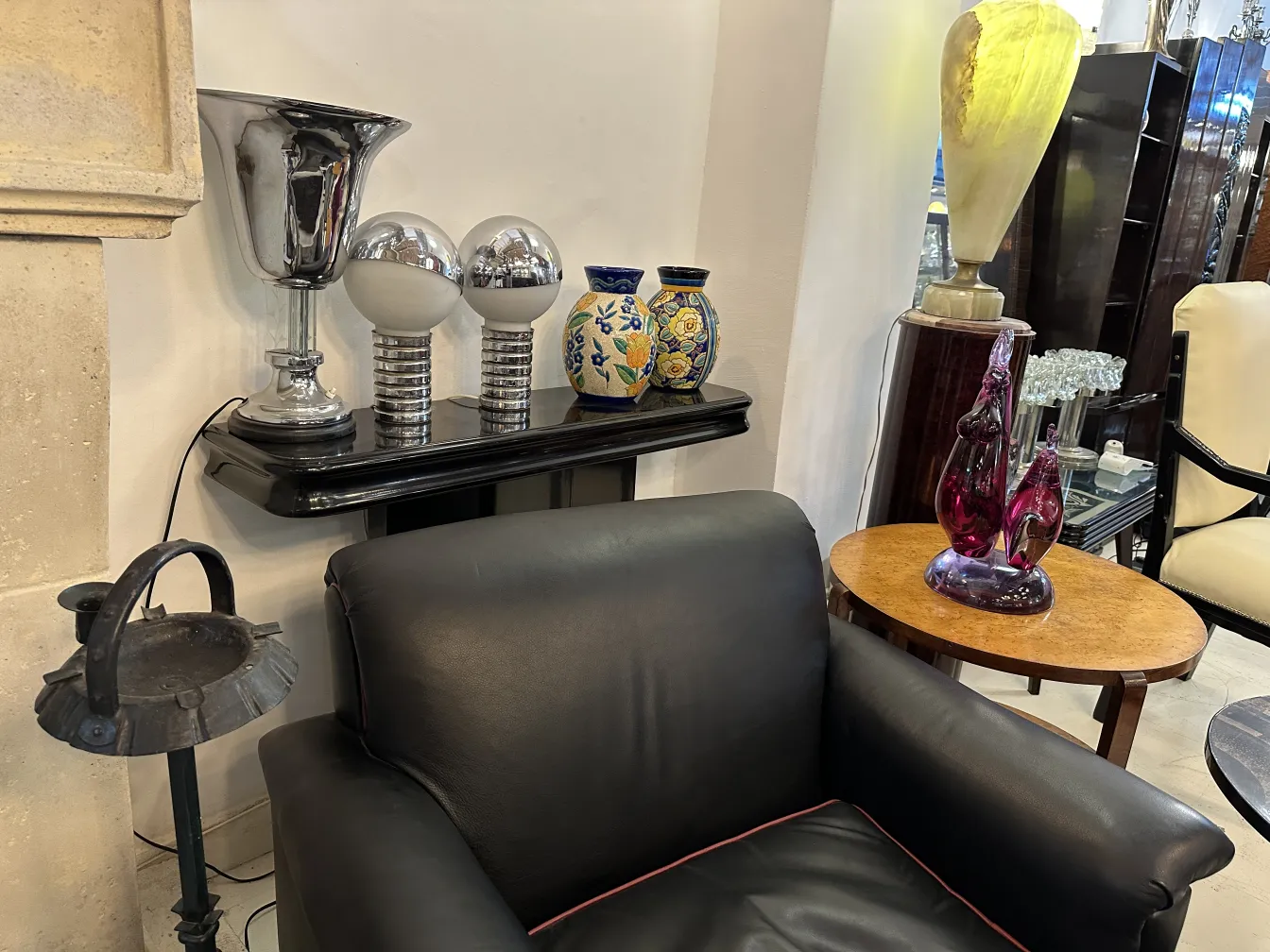 duas lâmpadas de mesa antigas com design elegante em uma sala com poltrona preta e decorações ao redor