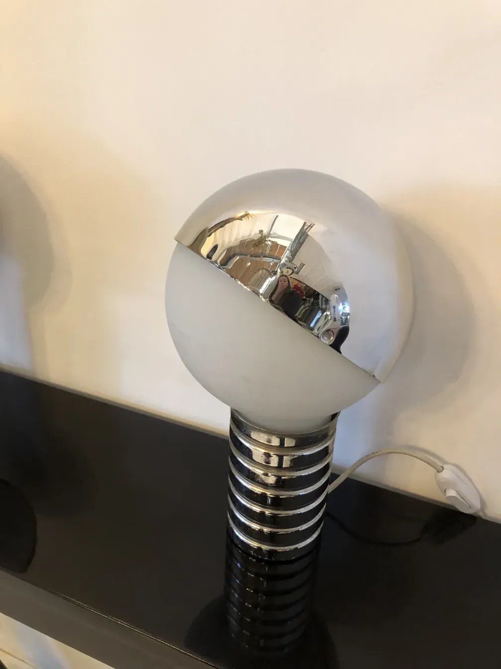 Duas lâmpadas de mesa antigas em um ambiente aconchegante, com base prateada e cúpula esférica branca.