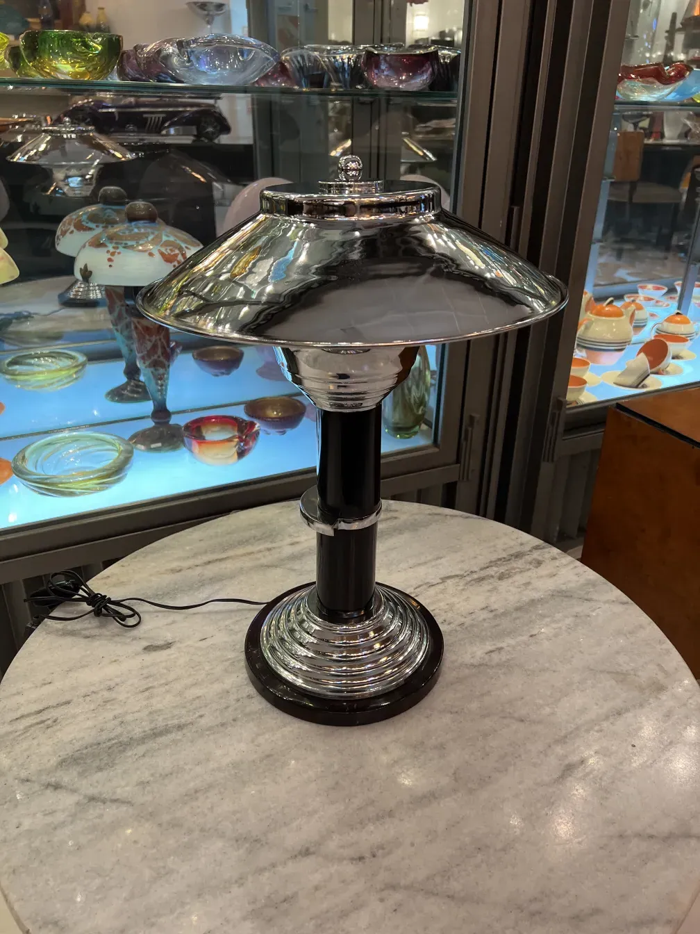 Vista de duas lâmpadas de mesa antigas com base decorativa e sombra de metal, colocadas sobre uma mesa