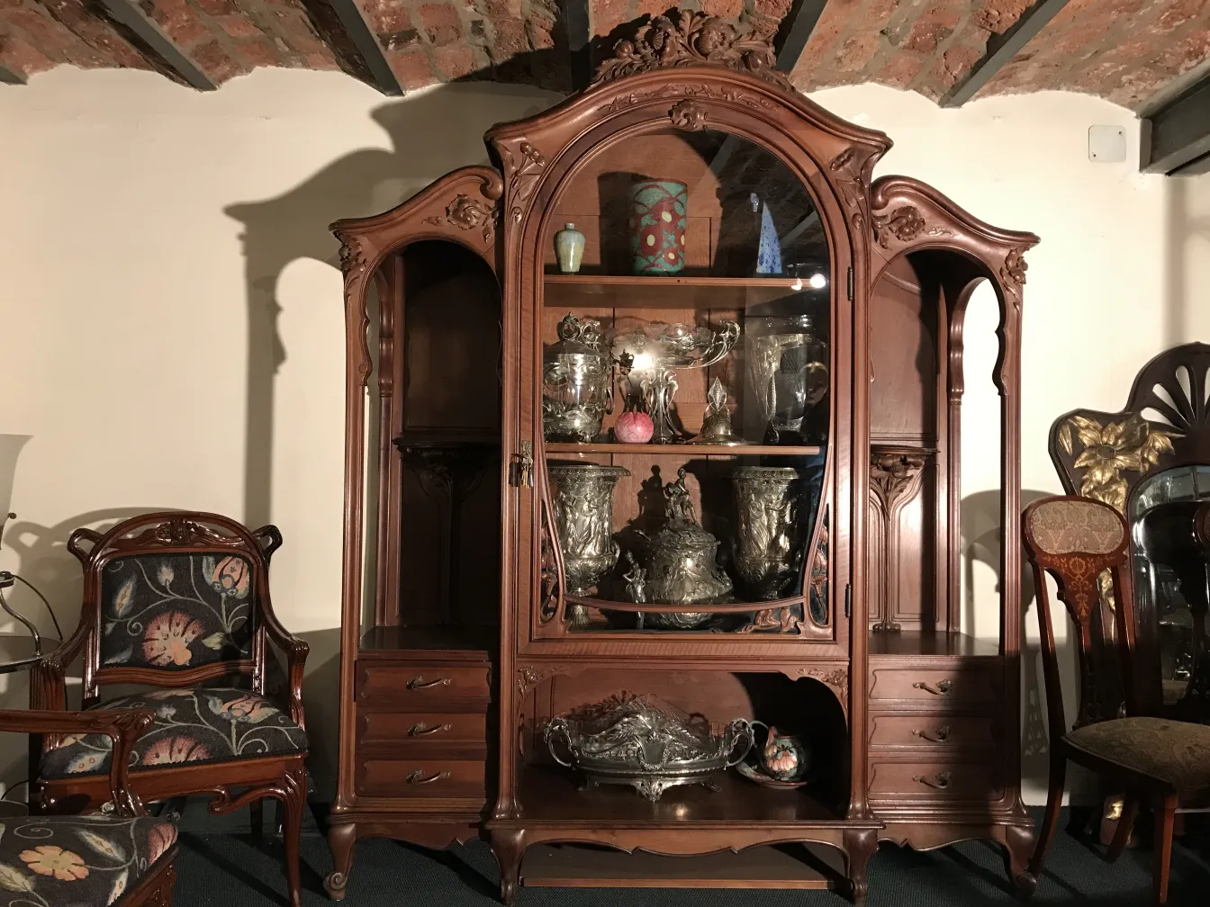 Antique display cabinet E.Dienst - Paris with decorative furniture and carved objects, cozy setting.