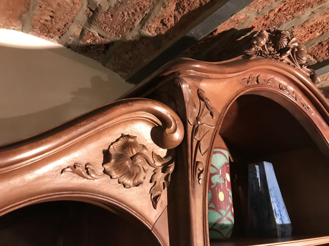 Antique display cabinet with floral carvings, cozy atmosphere