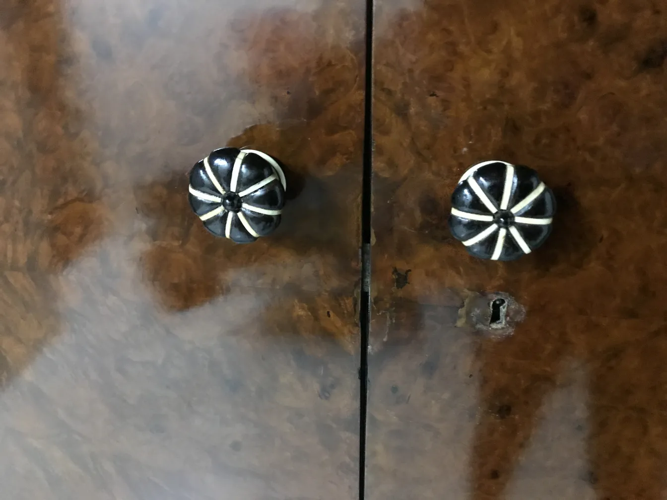 Antique display cabinet featuring two decorative knobs against a light wood background.