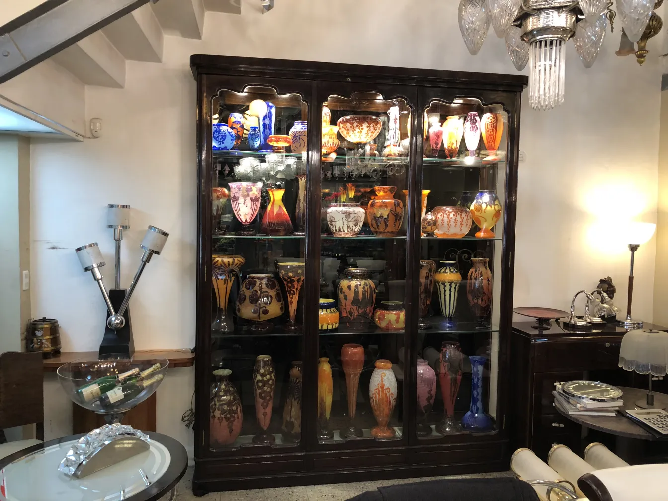 Antique display cabinet filled with colorful ceramic vases, set in an elegant environment.