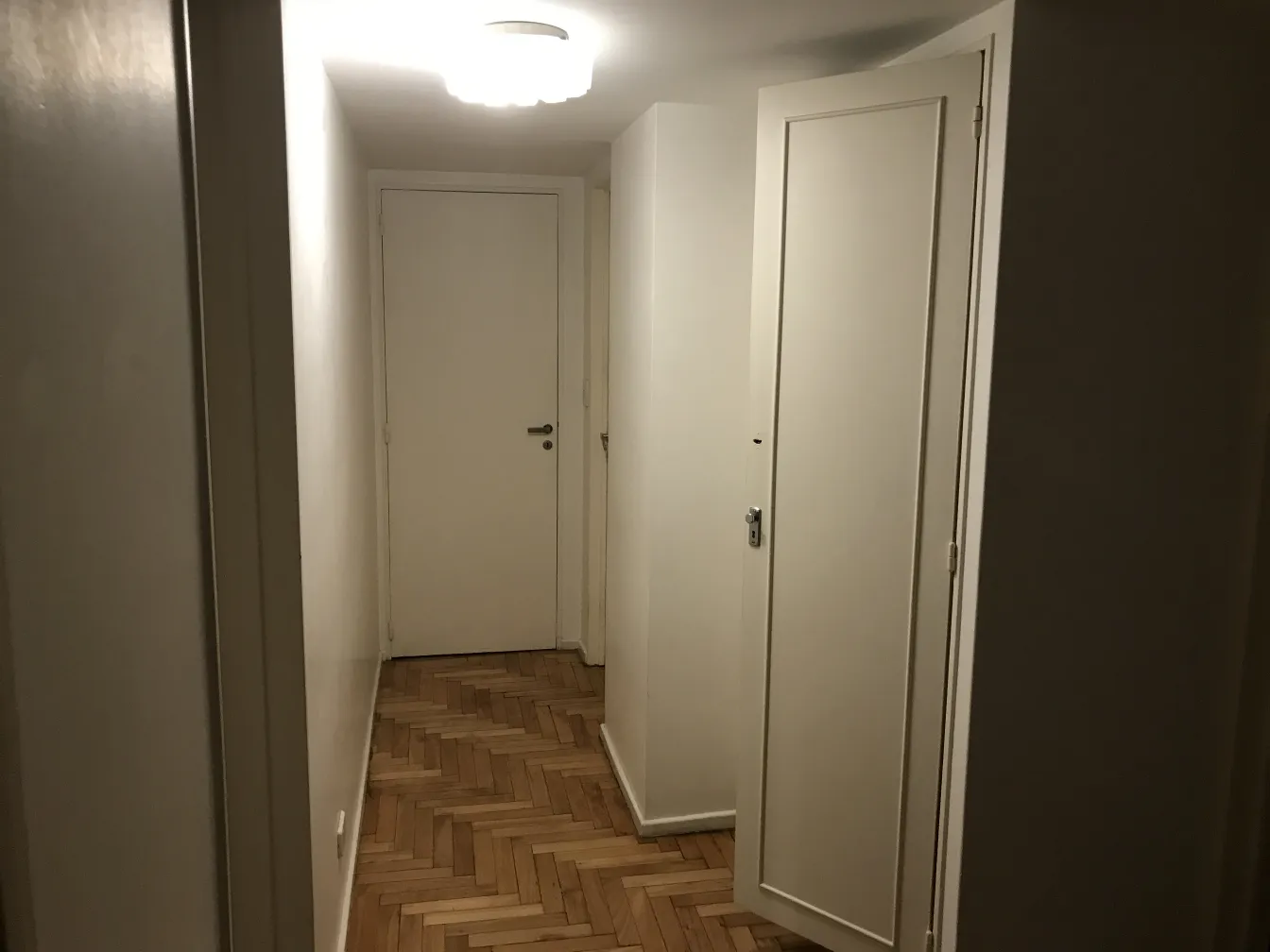 antique ceiling light illuminating a hallway with light walls