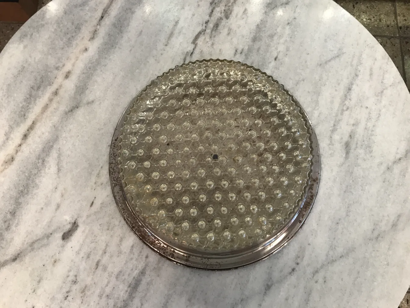 round antique ceiling light with textured surface and light bubbles