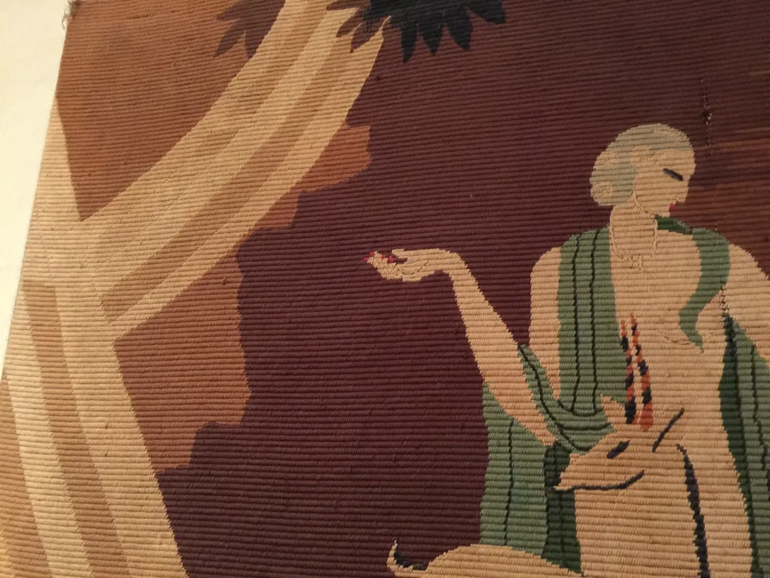 tapeçaria antiga com representação artística e detalhes sutis em cores, inclui figura humana e fauna