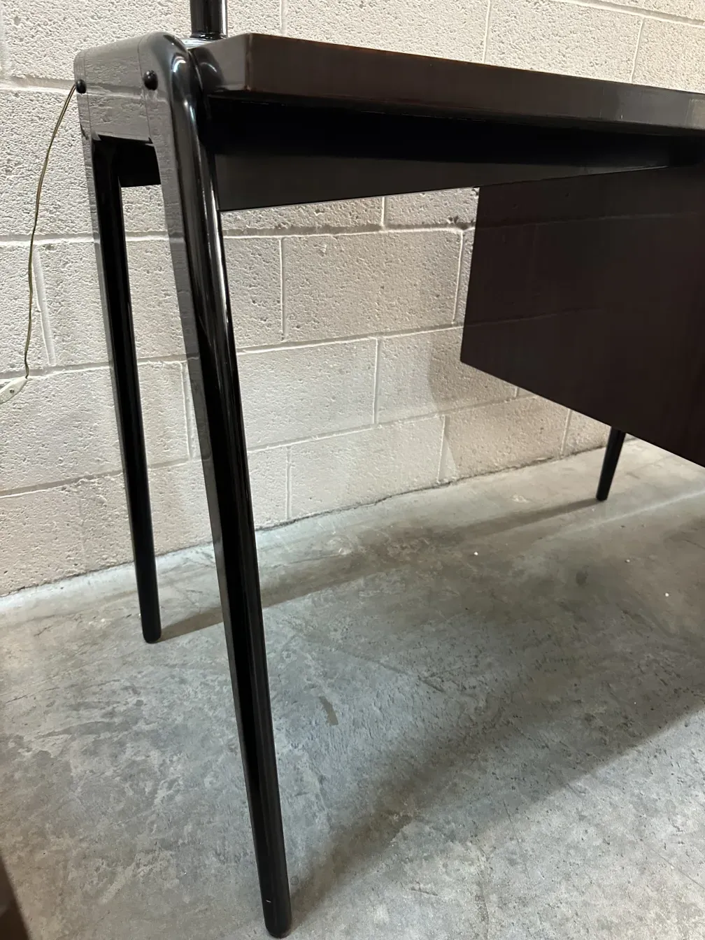 Side view of an antique desk with minimalist design, displayed in a simple setting.