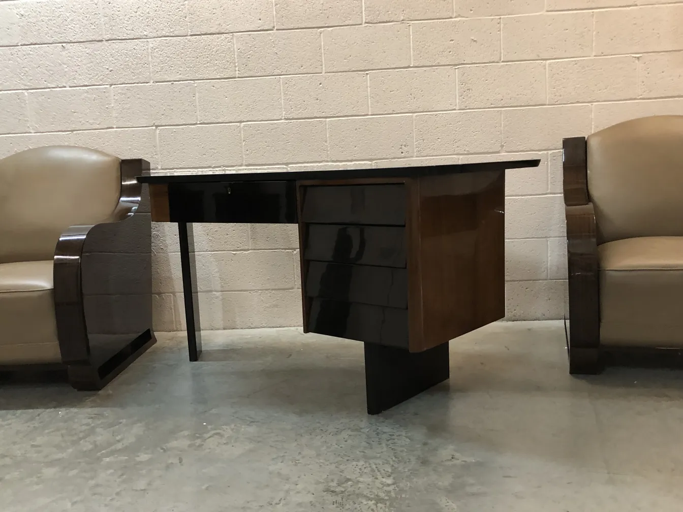 antique desk with dark details and a stylized shape, surrounded by armchairs