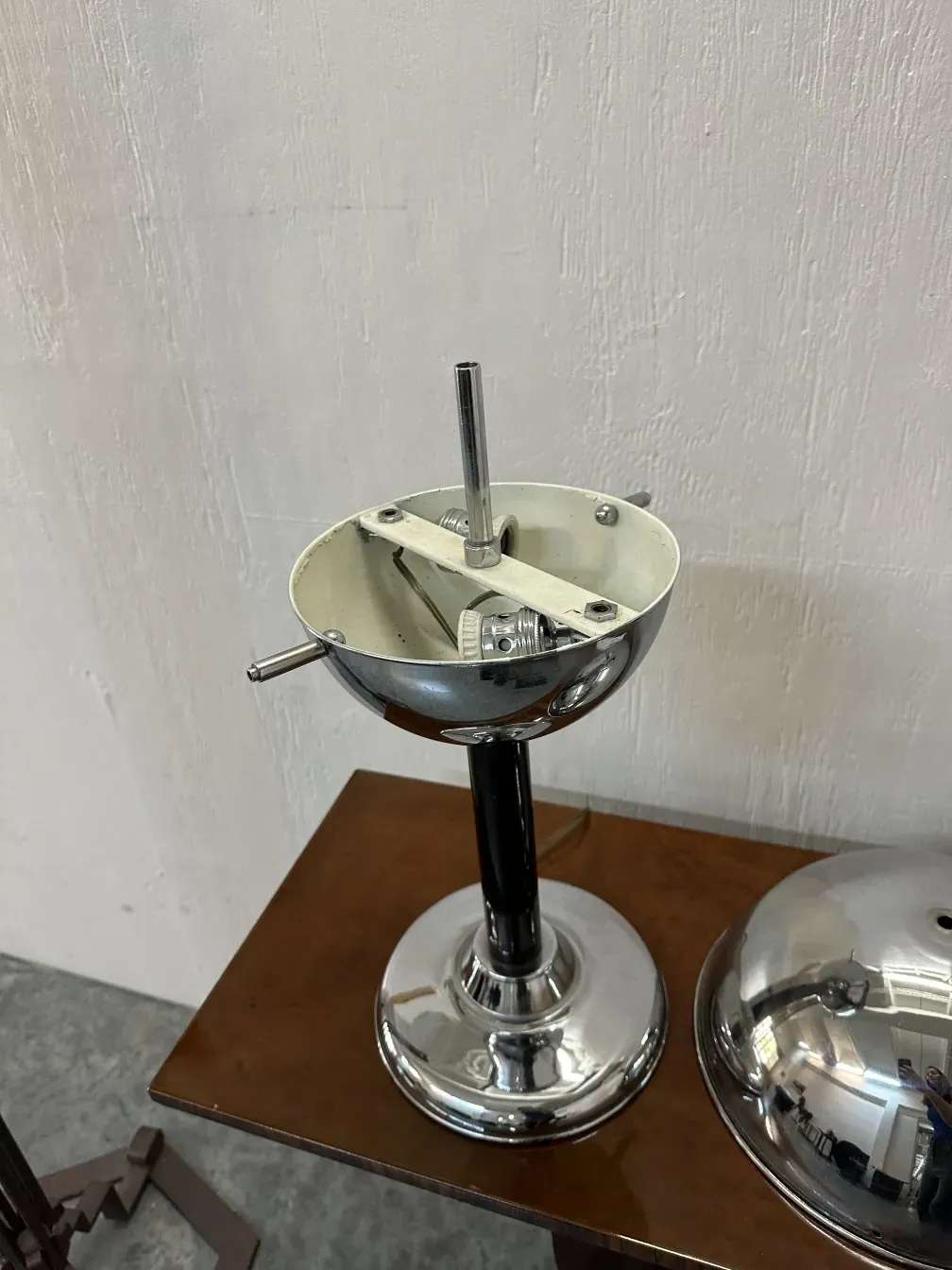 Antique table lamp with a shiny round metal base, classic style, in a neutral setting.