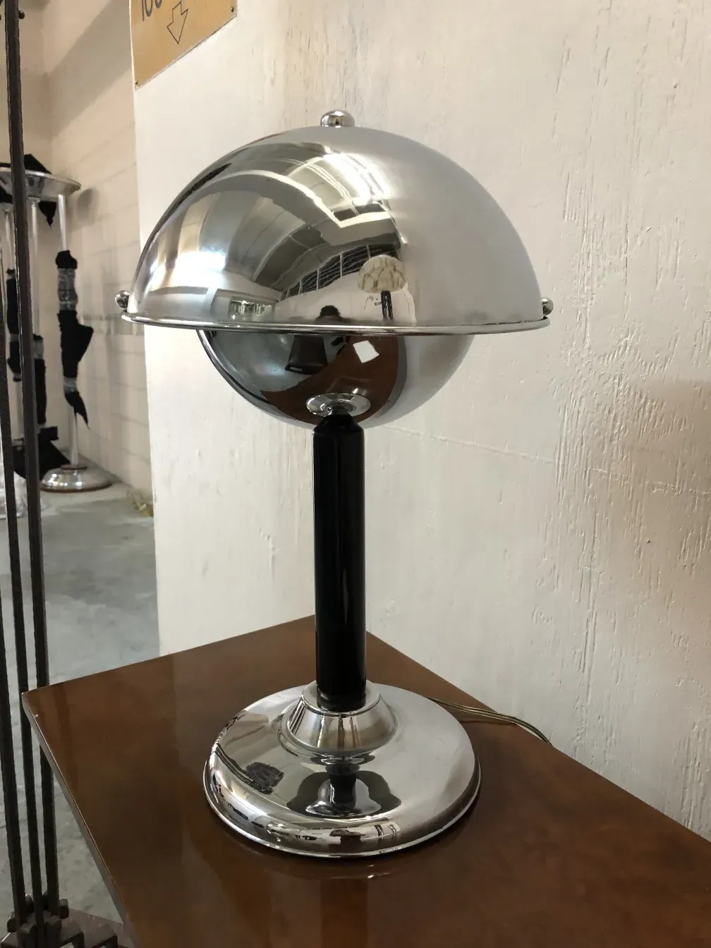 Antique table lamp with a conical shade and polished base, placed on a wooden table.