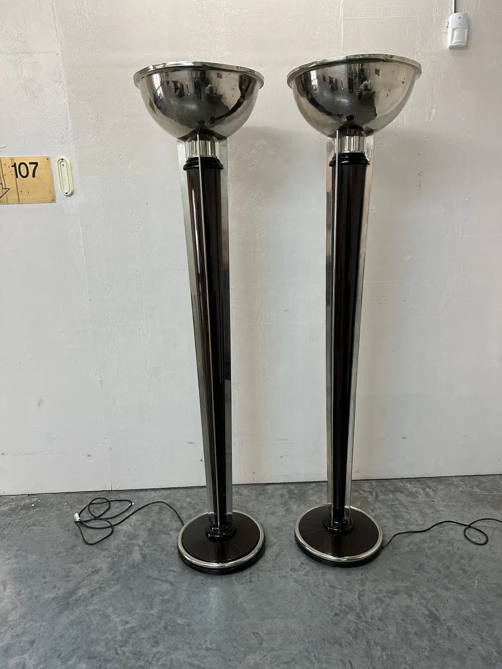Two antique floor lamps with rounded bases and shiny shades.