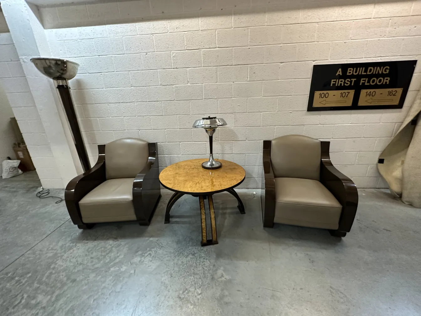 Two antique floor lamps with two armchairs and a table.